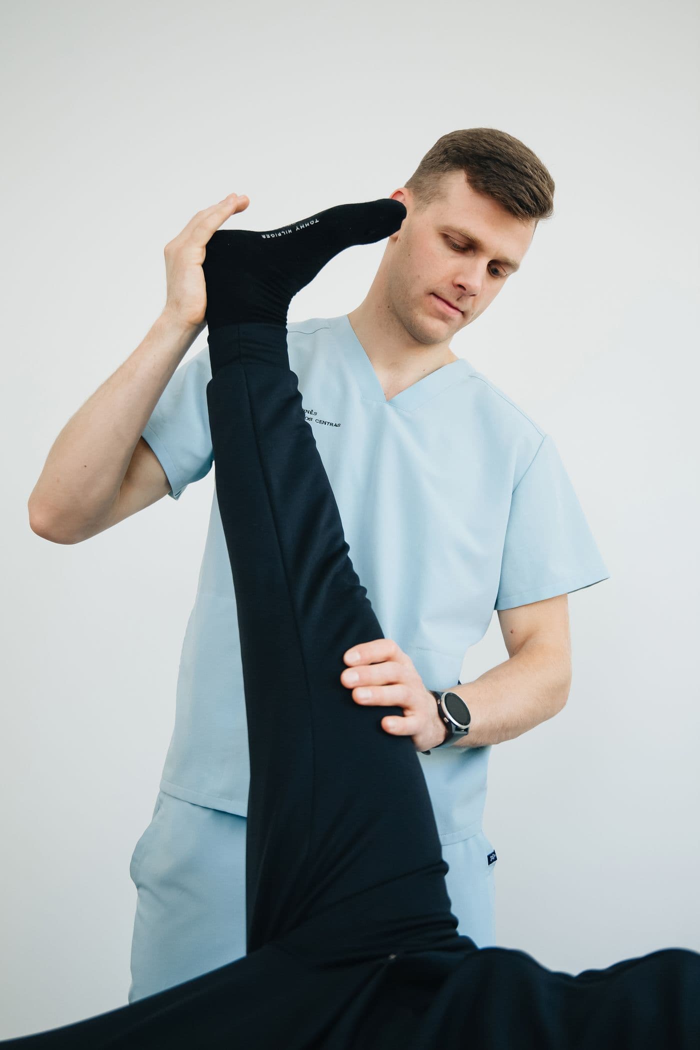 Therapist guiding a patient's leg through a supported stretch